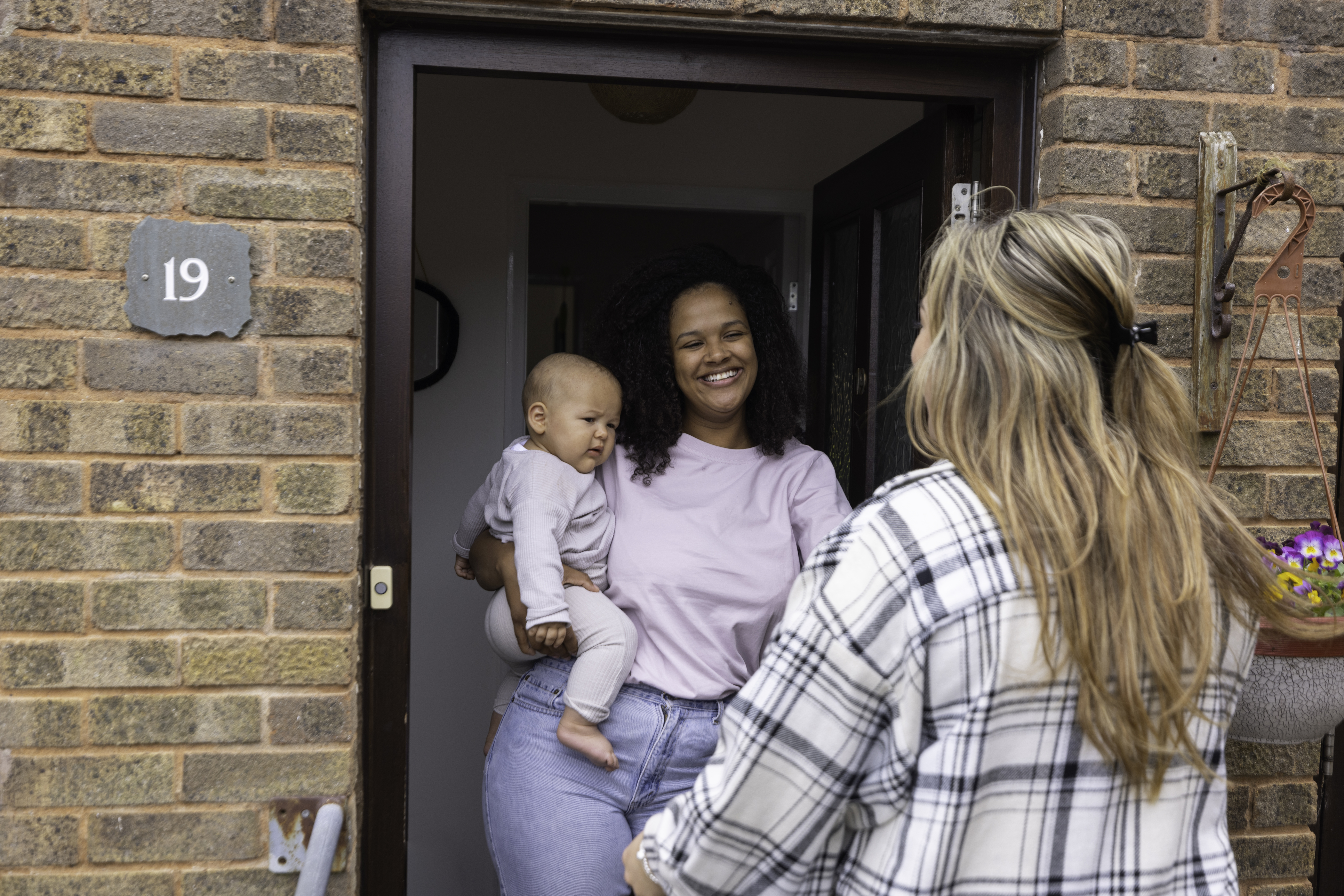 A new mother greeting her friend at the door